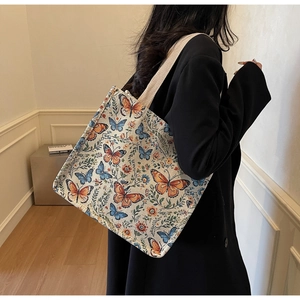Detail of floral jacquard tote bag with bow motifs carried by a model in a black blazer