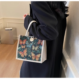 Detail of linen handbag featuring colorful butterfly embroidery and a vintage wood button