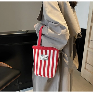 Detail of red and white striped canvas bucket bag with Nanciaojie label and red handle