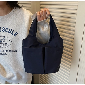 Dettaglio della borsa a secchiello in nylon blu scuro con doppie tasche e tessuto durevole