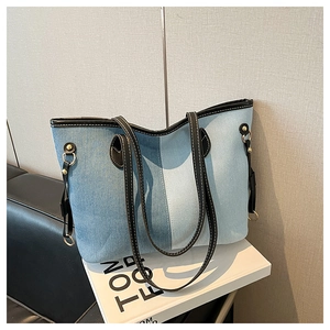 Detail of large denim patchwork tote bag with contrast stitching and leather handles