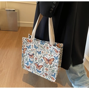 Detail of colorful butterfly jacquard pattern on a structured tote bag held by a model