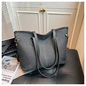 Detail view of large denim tote bag with V-shaped stitching and metallic studs on side
