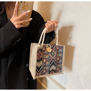 Detailed close-up of a geometric ethnic pattern handbag with woven handles and a wooden button