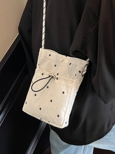 Minimalist white crossbody bag with small black flower pattern and drawcord front pocket
