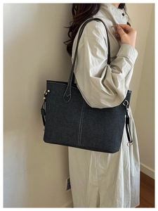 Detail of contrast stitching and gold metal hardware on denim tote bag side