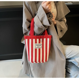 Detail of red and white striped canvas bucket bag with logo patch and handle