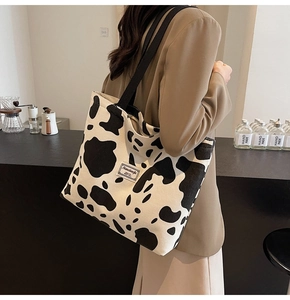 Detail of cow print corduroy tote bag with black straps and brand label on side
