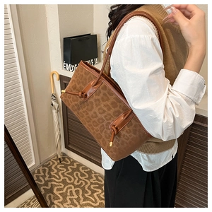 Close-up of leopard print tote bag with brown leather straps worn by a model