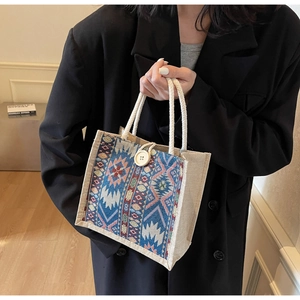 Detail of bohemian geometric woven handbag with cotton rope handles and large wood button