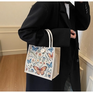 Detail of linen tote bag featuring butterfly floral print and woven rope handle