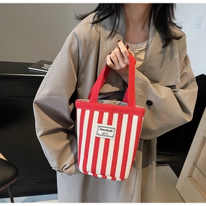 Detail of red and white striped canvas tote with durable woven handle and square brand patch