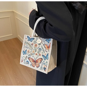 Detail view of linen tote bag featuring butterfly floral patterns and woven rope handles