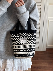 Ethnic style canvas bucket bag with geometric prints and woven handles held by a model