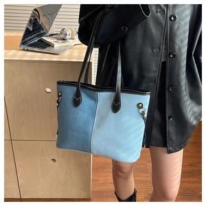 Close-up of contrast denim patchwork tote bag with black leather trim and gold studs