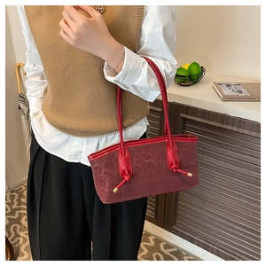 Close-up of a burgundy leopard print shoulder bag with knotted handle and gold hardware