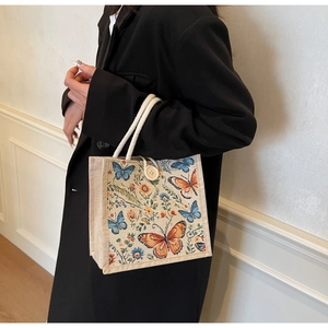Detail of linen tote bag with butterfly floral print and woven rope handles
