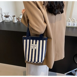 Detail of a striped canvas tote bag with thick handles for daily office and leisure use