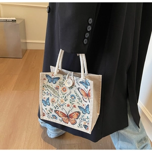 Close-up of linen tote bag with colorful butterfly floral print and rope handle
