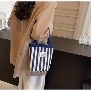 Detail of blue and white striped canvas handbag shown with an autumn coat