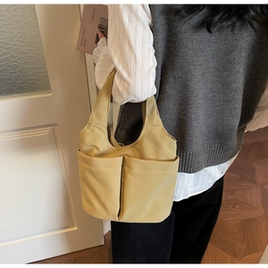 Dettaglio della grande borsa tote in tela beige con tasche frontali sulla spalla