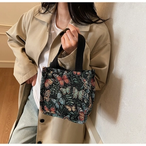 Detail of colorful butterfly tapestry tote bag with black canvas handle and woven texture