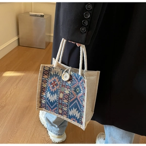 Detail of ethnic tote bag with geometric embroidery and rope handles on a model