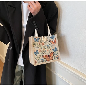 Detail of linen tote bag featuring butterfly floral weave and wooden button closure