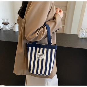 Detail of blue striped canvas tote bag with textile label and navy ribbon handles