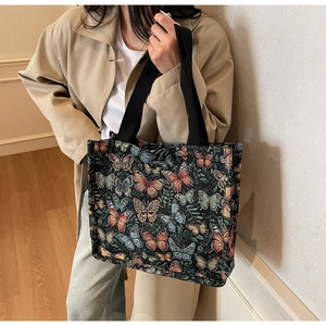 Detail of colorful butterfly jacquard pattern on a black fabric tote bag with twin straps