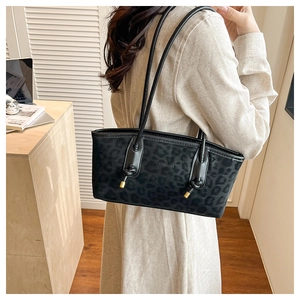 Detail view of leopard print tote bag with black shoulder straps and gold knot accents