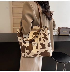 Detail of milk tea corduroy tote bag with brown cow print and minimalist woven label