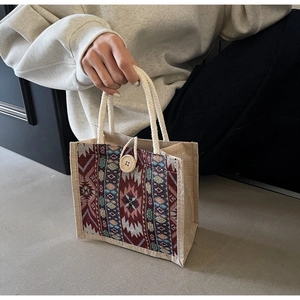 Detailed close-up of woven jute handbag with ethnic embroidery and wooden button closure