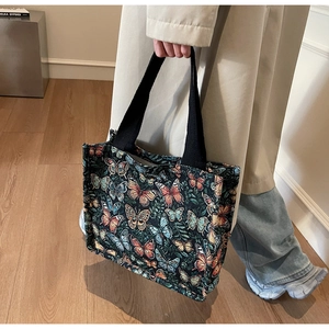 Detailed view of butterfly jacquard texture and black webbing straps on large tote bag