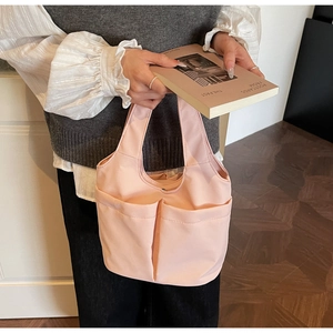 Dettaglio della borsa a secchiello in nylon rosa con ampie tasche anteriori