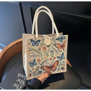 Detail of linen tote bag featuring butterfly floral embroidery and rope handles