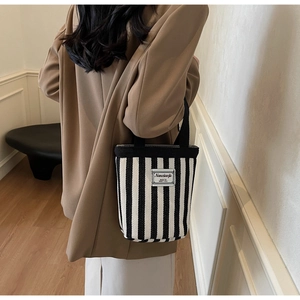 Detail of black and white striped canvas tote bag with woven handles and fabric label