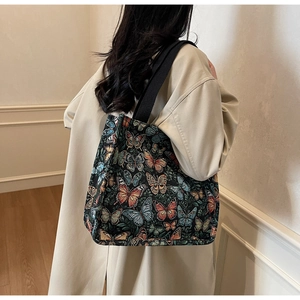 Detail view of a vintage tapestry tote bag with colorful butterfly embroidery and wide strap