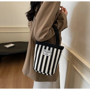 Close-up of a striped canvas tote bag featuring black and white vertical patterns and brand tag