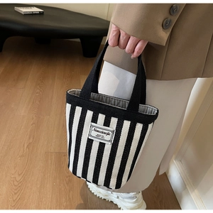Detailed shot of striped canvas tote bag with black handles and aesthetic label