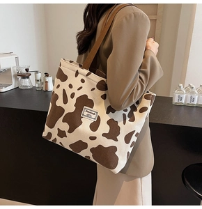 Close-up of textured corduroy tote bag with cow print and brand label on front