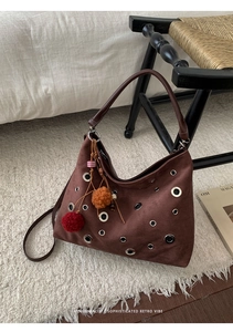 Close-up of vintage brown suede tote with metal eyelets and colorful tassel charm