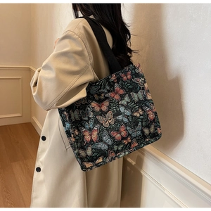 Detailed view of canvas tote bag featuring vibrant butterfly prints and black strap