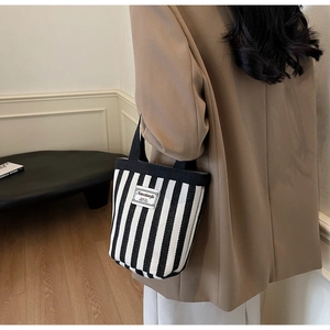Detail of striped canvas bucket bag featuring a black and white texture with embroidered label