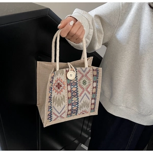 Detailed close-up of ethnic woven handbag with colorful geometric tribal patterns and button
