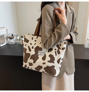 Detail of corduroy cow print tote bag with brown handles and branded textile label