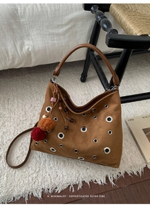 Detail of a brown suede hobo bag with silver grommets and colorful tassel charms