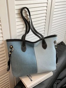 Contrast denim tote bag with blue patchwork and black leather trim on white background
