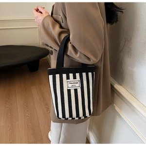 Detailed shot of a striped canvas bucket bag with wide woven handles in a lifestyle setting