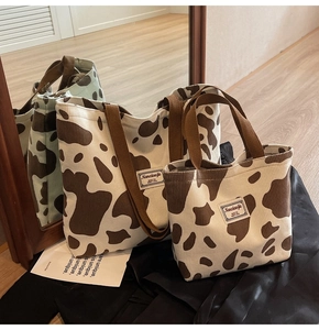 Detail of cow-print corduroy tote bags in two sizes with brown woven handles